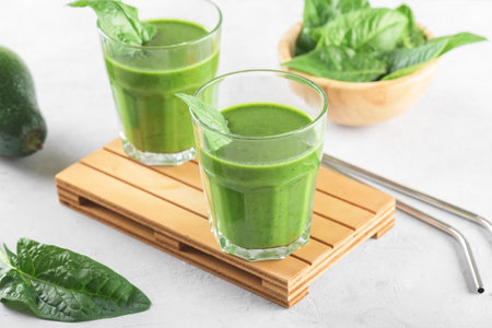 Healthy green smoothie with spinach, avocado, banana, and vegan milk in two glasses and fresh ingredients on light gray table background. Detox, diet, healthy, vegetarian food conceptの写真素材
