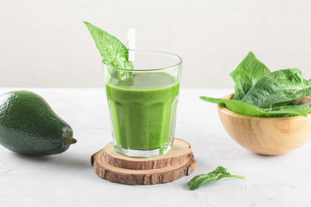 Healthy green smoothie with spinach, avocado, banana, and vegan milk in glass and fresh ingredients on light gray background. Detox, diet, healthy, vegetarian food conceptの写真素材