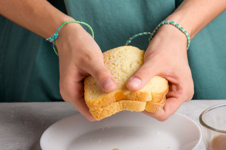 woman hands holding a sandwich with honey and peanut butter of wheat bread on white plate, to have a...
