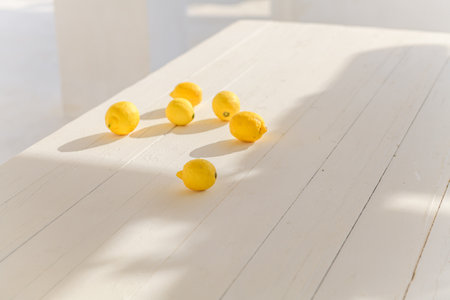 Some yellow ripe lemons on a white wooden table background, summer, hard shadowsの写真素材