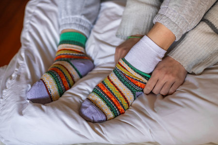 A woman in warm pants putting on a second pair of warm socks to keep warm in the winterの写真素材