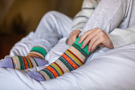 A woman in warm pants putting on a second pair of warm socks to keep warm in the winter without heatingの写真素材