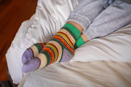 woman legs with socks posing in winter sitting on a couch at home, puts on socks.の写真素材