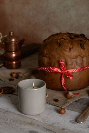 Traditional Italian Christmas Cake Panettone with red bow and lit candle on wooden rustic table background. Homemade artisan sourdough panettone ready for eating. Classic Christmas Food Edible giftの写真素材