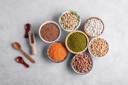 Mixed legumes for vegetarian and vegan cooking on gray table. Red lentins, White beans, green mung beans, cranberry beans in the bowls, pulses for healthy balanced diet, plant-based protein sourceの写真素材