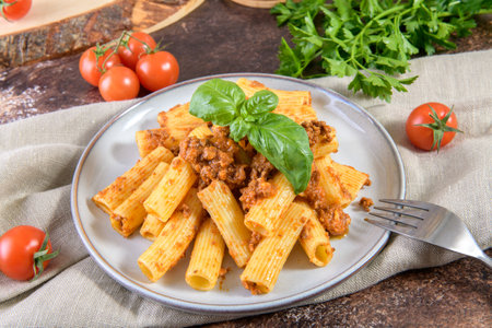 Rigatoni pasta dish with Bolognese sauce and fresh basil leavesの写真素材