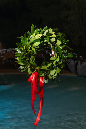 laurel wreath made of fresh leaves is adorned with red ribbon as graduation simbolの写真素材