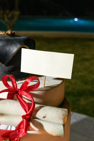 Blank Card Mockup on a Decorative Graduation Cake and Red Ribbon at Outdoor Partyの写真素材