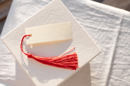 Blank card with Red Tassel Displayed on white gift boxの写真素材