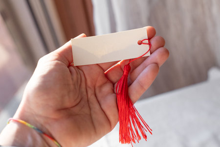 Handheld Blank Card Mockup With Red Tassel in Natural Lightの写真素材