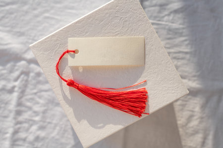 Blank card with Red Tassel Displayed on white gift boxの写真素材