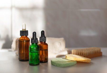 Three cosmetic glass dropper bottle with black lid on white background in natural sunshine and shadows. Skincare products, natural cosmetic. Beauty concept for face and body careの写真素材