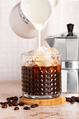 Cream milk is pouring into iced brew coffee, refreshing summer drinkの写真素材