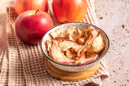 Dried apple slices in a bowl with fresh apples on sunny kitchenの写真素材