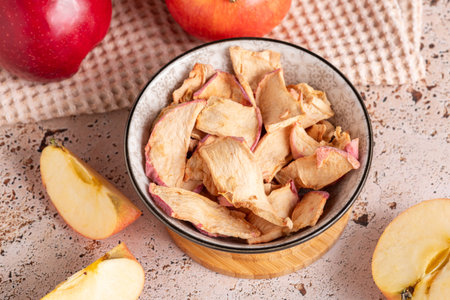 Healthy apple dried snack in ceramic bowl on sunny kitchenの写真素材