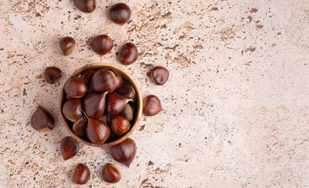Autumn chestnuts in rustic wooden bowl on beige backgroundの写真素材