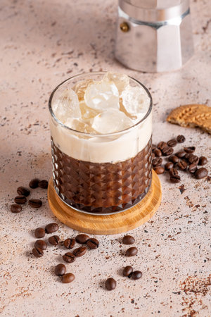 Iced creamy coffee with milk and moka pot in simple modern setup. on beige kitchen table background. Coffee break during a hot summer day, refreshing drinkの写真素材