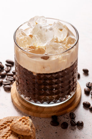 Espresso creamy iced coffee with scattered coffee beans on textured stone table, close upの写真素材