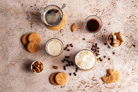 Different types of coffee drinks with cookies on a beige table, top view. Iced coffee, espresso, espresso with milk, brew coffee with almond and whole grain cookiesの写真素材
