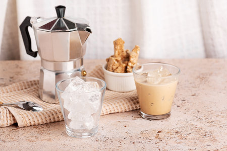 Iced coffee, espresso cups with ice and moka pot on textured beige stone tableの写真素材