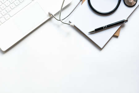 Workplace of doctor with laptop and stethoscope on keyboard and notepad with pen isolated. Close up. Concept medical, business.の写真素材