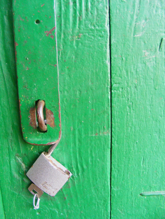 Old wooden doors are locked with a metal padlockの写真素材