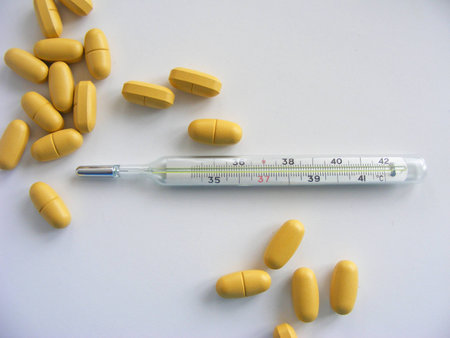 pills and thermometer on white background