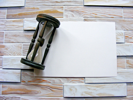 Wooden hourglass with place for writing on the wooden wall backgroundの写真素材