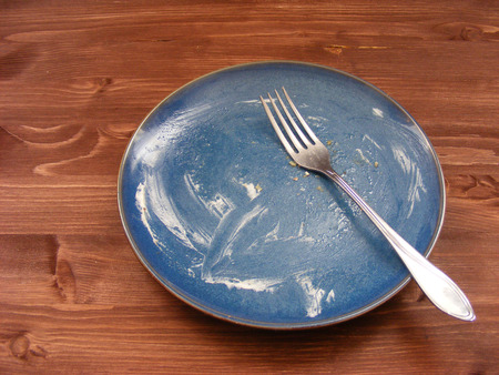 Empty dirty plate with forks on the wooden table, conceptual imageの写真素材