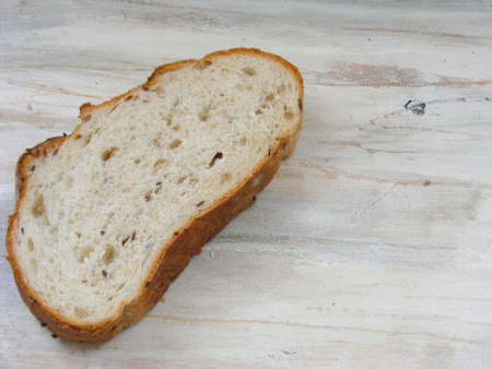 Slice of bread on shabby wooden background, loaf of bread on wooden plate
