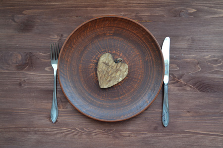 Flat view of wooden heart on plate. Romantic symbol. Dinner plate background. Valentine decoration.の写真素材
