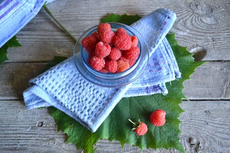 Pot of big shinny raspberries over blue napkin and shabby table. Summer healthy food. Morning...