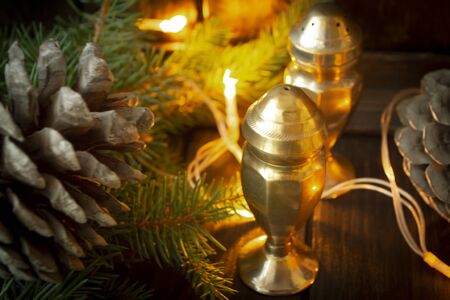 A set of silver salt and pepper shakers with pine branch, cone and illumination.