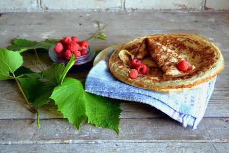 Plate with delicious thin pancakes and fresh berries on rustic wooden shabby table
