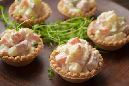 Canapes in tartlets, Russian snack. Wooden table, tartlet with russian salad for catering.の写真素材