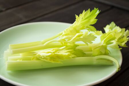 fresh celery sticks on green plate and dark table