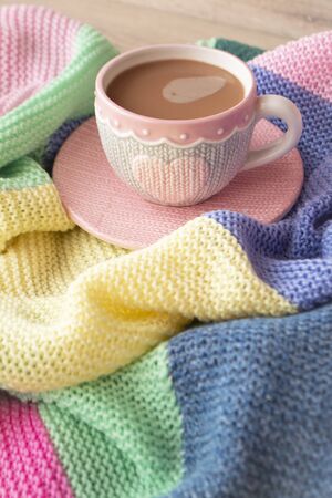 Knitted effect cup with cappuccino, colorful pastel giant plaid, morning concept, vertical imageの写真素材