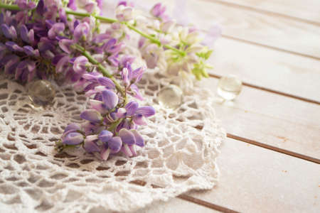 lovely lupine and vintage lace on rustic white wooden background in light, floral greeting card.