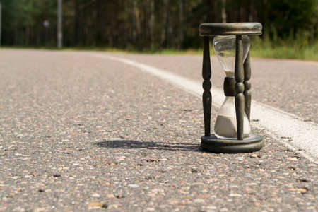 Time concept alarm hourglass on the asphalt road
