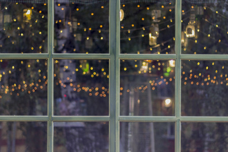 Window with green wooden frame on front of house, christmas decoration  with garland lightsの写真素材