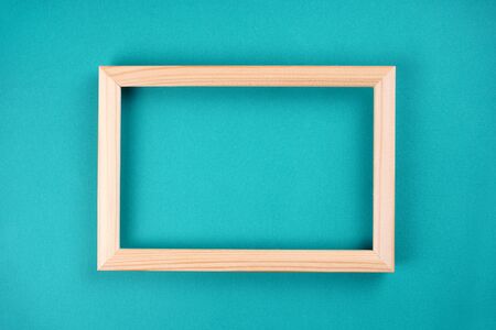 Wooden frame on bright turquoise background. Flat lay, copy space, top view, mock up