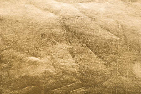 Old gold paper. Golden texture Uneven background with the effect of distressed, scratches, bumps, creases, folds and fadin, attrition, abrasionの写真素材