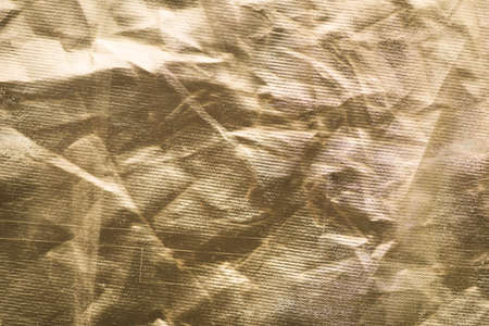 Old gold paper. Golden texture Uneven background with the effect of distressed, scratches, bumps, creases, folds and fadin, attrition, abrasionの写真素材