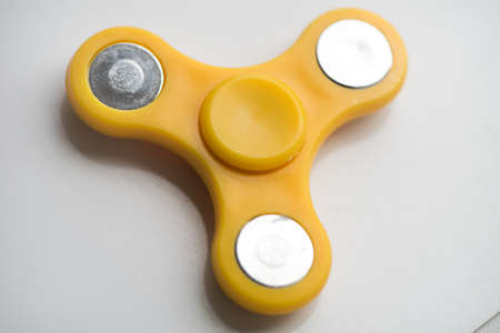 Yellow  Hand Spiner. Stress relieving toy on white background. Close-up. Top view. Stock photo.の写真素材