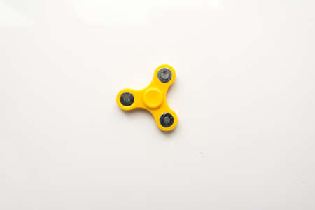 Yellow  Hand Spiner. Stress relieving toy on white background. Close-up. Top view. Stock photo.の写真素材