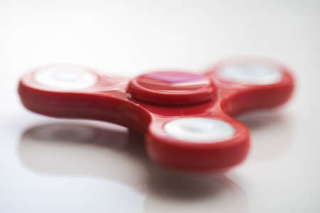 Red  Hand Spiner. Stress relieving toy on white background. Close-up. Top view. Stock photoの写真素材