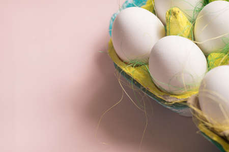 White chicken eggs in colored paper eco-friendly packaging with decorative sisal.