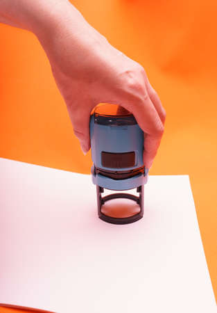 Woman's hand with the seal, stamp.  Process stamping the contract, documents, close up.