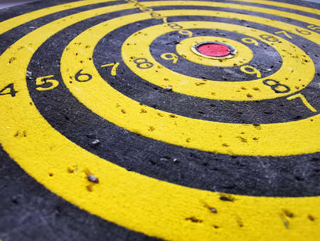 Target for throwing Darts. Black and yellow concentric circles with digital markings and dart marks....