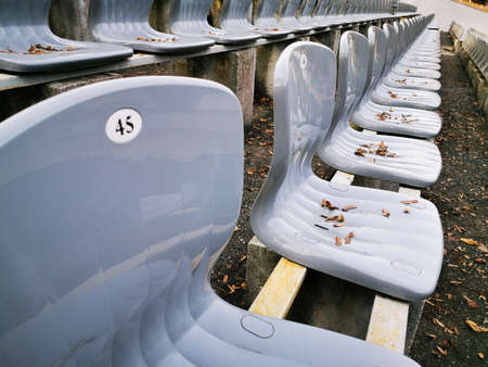 Rows of plastic gray seats in a public Park in front of the stage. Empty chairs covered with autumn...
